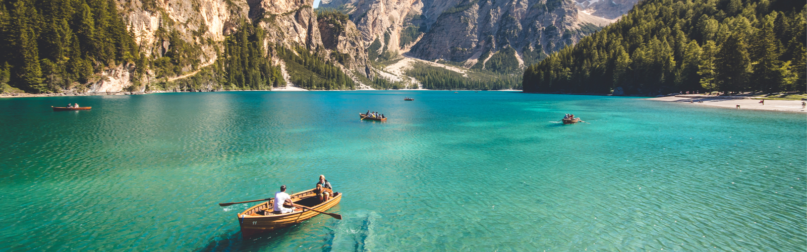 People in canoes on a lake with mountains in the background