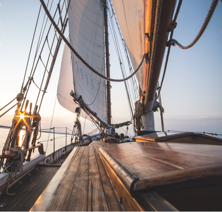 The front of a large sailboat at sunset